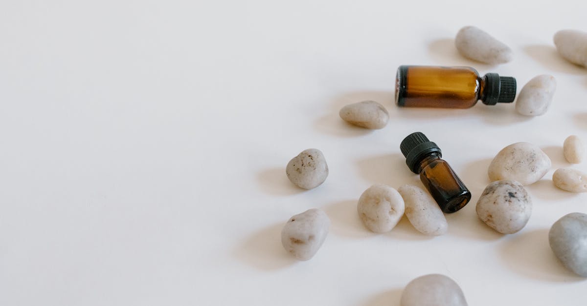 Minimalist arrangement of essential oil bottles surrounded by stones on a light background.