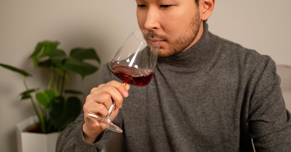 Adult man enjoying red wine indoors, focused on aroma. Cozy, relaxed setting.