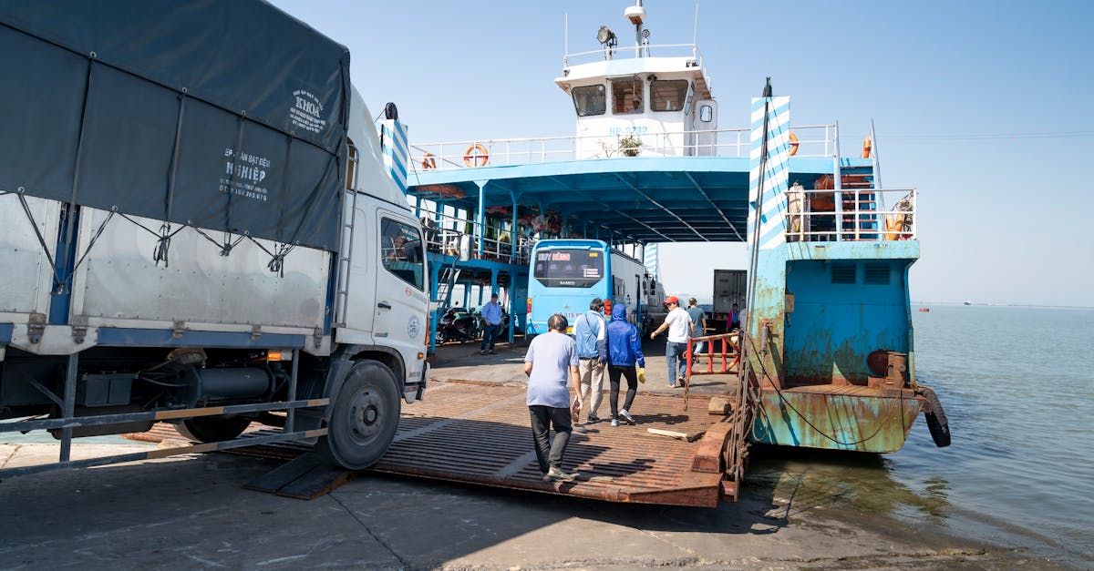 A bustling ferry scene with trucks and people boarding under a clear sky, showcasing busy port life.